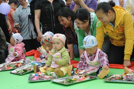 Babies grab lots at a school in Shifang City, southwest China's Sichuan Province, on May 13, 2009. The Luohan (Arhat) Temple in Shifang took in all the lying-in pregnant women as the neighbouring Maternal and Child Care Service Center of Shifang was dilapidated by the earthquake on May 12, 2008. 