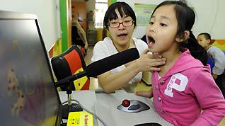 Zhe Ping teaches her deaf student Lu Xinlei to pronounce in a special education nursery school in Shenyang, on May 13, 2009. The nursery school started in 1994, and has taught some 1000 disabled students during the past 15 years.