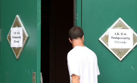 A man walks into the IS 5 school with a temporarily closed note sticked on its gate in Elmhurst of Queens borough of New York, the US, on May 15, 2009. Three New York City public schools in its Queens borough, IS 238 in Jamaica, PS 16 in Corona and IS 5 in Elmhurst, were closed on Friday due to reports of many children with flu-like symptoms. 