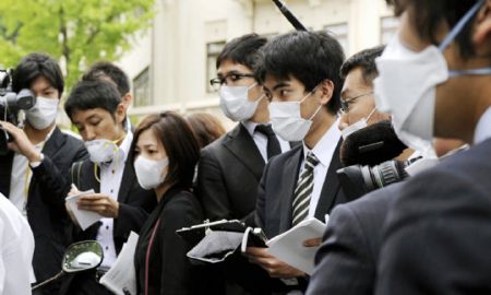 Journalists with facemasks work at the high school where the confirmed A/H1N1 patient studies in Kobe city, Japan, on May 16, 2009. Japan's first domestic case of A/H1N1 flu was confirmed on Saturday. The patient is a 17-year-old male high school student in Kobe city, who has no records of overseas travel, according to the Ministry of Health, Labor and Welfare. 