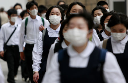 People wearing masks walk on a street in Tokyo, on May 19, 2009. The latest statistics showed that the number of A/H1N1 influenza cases in Japan has risen to 178 after 15 more patients were confirmed on Tuesday. 