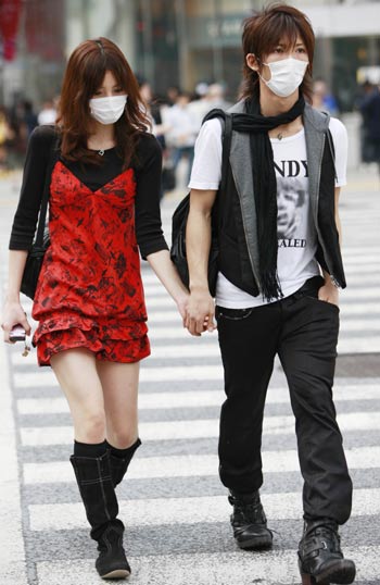 People wearing masks walk on a street in Tokyo, on May 19, 2009. The latest statistics showed that the number of A/H1N1 influenza cases in Japan has risen to 178 after 15 more patients were confirmed on Tuesday.