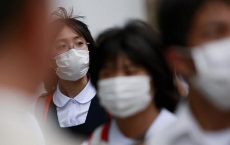 People wearing masks walk on a street in Tokyo, on May 19, 2009. The latest statistics showed that the number of A/H1N1 influenza cases in Japan has risen to 178 after 15 more patients were confirmed on Tuesday.