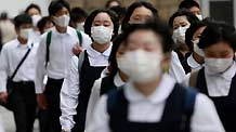 People wearing masks walk on a street in Tokyo, on May 19, 2009. The latest statistics showed that the number of A/H1N1 influenza cases in Japan has risen to 178 after 15 more patients were confirmed on Tuesday.