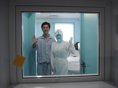 An isolated patient whose surname is Qin and a nurse wave to reporters at the isolation ward at the Beijing Ditan Hospital in Beijing, capital of China, on May 20, 2009. 