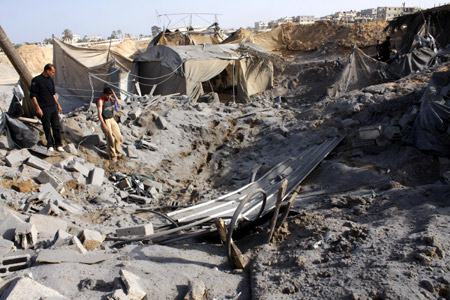 Palestinian men inspect the damaged smuggling tunnel linking the southern Gaza Strip town of Rafah with Egypt following an overnight Israeli air strike in Gaza Strip, on May 20, 2009. 