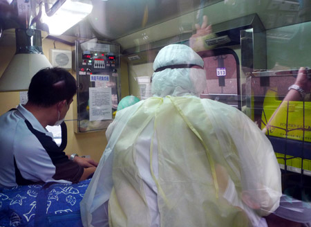 One of the family members, who were on the same plane as the man confirmed of A/H1N1 influenza, is attended by a quarantine worker at a hospital in Taipei, southeast China's Taiwan, on May 20, 2009. Taiwan reported its first case of H1N1 flu Wednesday. The man is a 52-year-old foreign doctor who arrived by air in Taipei from the US on Tuesday night. 