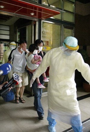 A family, who were on the same plane as the man confirmed of A/H1N1 influenza, are led by quarantine workers at a hospital in Taipei, southeast China's Taiwan, on May 20, 2009.