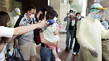 A family, who were on the same plane as the man confirmed of A/H1N1 influenza, are led by a quarantine worker at a hospital in Taipei, southeast China's Taiwan, on May 20, 2009.