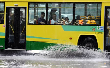 A bus runs in the rain in Guangzhou, capital of south China's Guangdong Province, on May 20, 2009. A rainstorm hit Guangzhou Wednesday and affected drainage system and traffic.