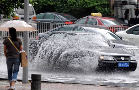 Cars run in the rain in Guangzhou, capital of south China's Guangdong Province, on May 20, 2009. A rainstorm hit Guangzhou on Wednesday and affected drainage system and traffic. 