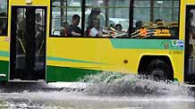 A bus runs in the rain in Guangzhou, capital of south China's Guangdong Province, on May 20, 2009. A rainstorm hit Guangzhou Wednesday and affected drainage system and traffic.