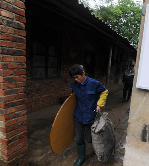 Chinese local residents collect and transfer their belongings after their residence was destroyed by rolling stones when a heavy rain hit Liuzhou City, southwest China&apos;s Guangxi Zhuang Autonomous Region, on May 20, 2009.