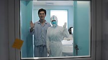 An isolated patient whose surname is Qin and a nurse wave to reporters at the isolation ward at the Beijing Ditan Hospital in Beijing, capital of China, on May 20, 2009.