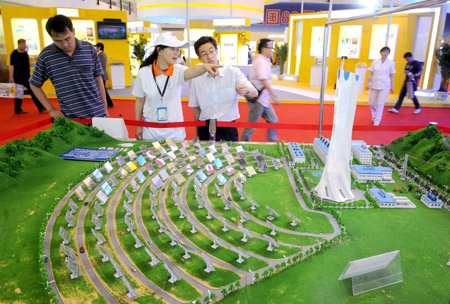 Visitors look at a model of a solar power station which is planned to be built in Badaling Town, Yanqing County of Beijing, during the 12th China Beijing International High-Tech Expo in Beijing, capital of China, on May 20, 2009.