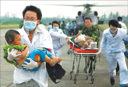 A volunteer from Sichuan University carries Lin Yang, 2, in his arms from a helicopter on May 21 last year after landing with evacuees to Chengdu, the capital of Sichuan Province, following the May 12 earthquake in Wenchuan County.