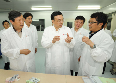 Chinese Vice Premier Li Keqiang (C) talks with a staff member of Sinovac, known in China as Beijing Kexing Bioproducts Limited Company, in Beijing, capital of China, on May 29, 2009. Li Keqiang urged vaccine companies to step up the preparation work for vaccine production after the first domestic A/H1N1 influenza case was confirmed in southern Guangdong Province on Friday. 