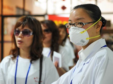 A quarantine official (R) guides passengers for temperature examination at the Maweigang dock in Fuzhou, capital of southeast China's Fujian Province, May 30, 2009. The third case of A/H1N1 in Fujian was confirmed in Fuzhou on May 29. 