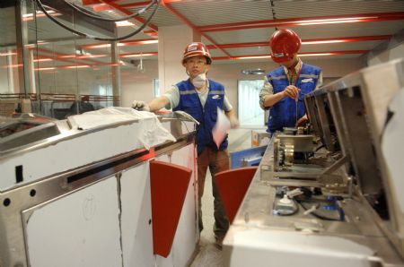 Workers adjust the automatic ticketing machine at a station of Beijing Subway Line 4 in Beijing, capital of China, on May 31, 2009. Beijing Subway Line 4 of about 28 kilometers began test operation on May 31. It will be put into use at the end of September.