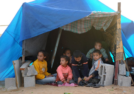 Photo taken on January 26, 2009 shows Palestinian children rest at a makeshift tent near their destroyed house at Mussani Village, 3 km south of Gaza City, after the Israeli operation of Cast Lead. Due to the conflicts between Israel and Palestine, most Palestinian children live in poverty and hardship, and they can hardly enjoy the happiness of their childhood.