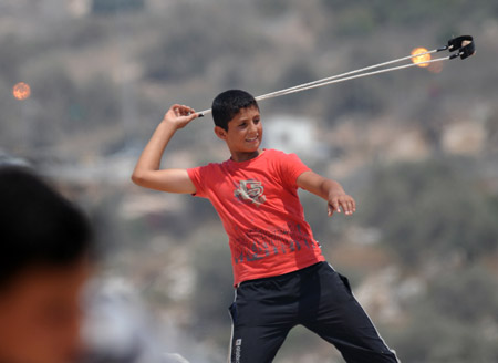 Photo taken on August 22, 2008 shows a Palestinian boy throwing a stone to Israeli soldiers in the West Bank village of Naal'in, west of Ramallah.