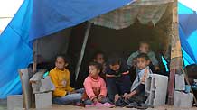 Photo taken on January 26, 2009 shows Palestinian children rest at a makeshift tent near their destroyed house at Mussani Village, 3 km south of Gaza City, after the Israeli operation of Cast Lead. Due to the conflicts between Israel and Palestine, most Palestinian children live in poverty and hardship, and they can hardly enjoy the happiness of their childhood.