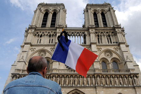 A man holds the French national flag while attending the memorial ceremony in front of Notre-Dame cathedral in Paris, capital of France, on June 3, 2009. 