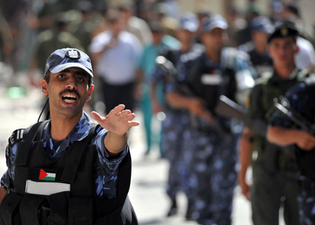 A Palestinian policeman dispels residents near the scene of the gunbattle in the northern West Bank city of Qalqilya on June 4, 2009. Three Hamas militants and a Palestinian policeman were killed in gunbattles between Hamas militants and Palestinian security forces in Qalqilya on Thursday. 