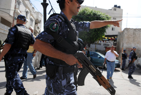 A Palestinian policeman dispels residents near the scene of the gunbattle in the northern West Bank city of Qalqilya on June 4, 2009. 