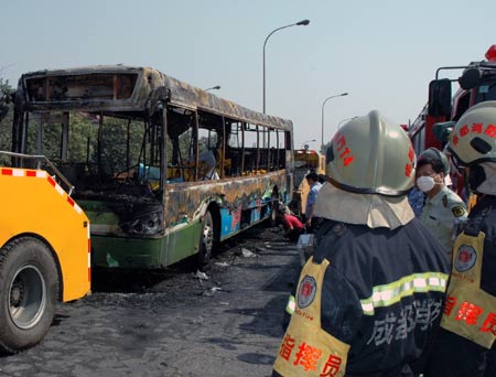 Firefighers and policemen investigate at the spot of a fire broke out on a public bus in Chengdu, capital of southwest China's Sichuan Province, on June 5, 2009. A fire broke out on the bus, killed at least 24 people on Friday.