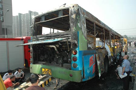 Firefighers and policemen investigate at the spot of a fire broke out on a public bus in Chengdu, capital of southwest China&apos;s Sichuan Province, on June 5, 2009. 