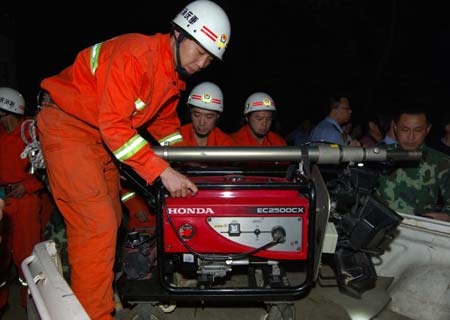 Fire fighters load the rescue equipment onto a pickup near the site of landslide at an iron ore mining area in southwest China's Chongqing Municipality, southwest China, June 5, 2009. At least 80 people are feared buried in the landslide in Chongqing on Friday, according to the local government. Rescuers had pulled out seven injured people, including four seriously hurt, from the debris as of 8:30 p.m., according to the publicity department of Wulong County, the site of the accident. 