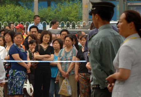 Relatives wait outside an exam site of a middle school during the college entrance exam in Beijing, capital of China, on June 7, 2009. China's national college entrance exam kicked off on Sunday with about 10.2 million registered examinees.