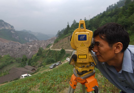A worker monitors the mountain massif prior to the second blasting in Wulong County of southwest China's Chongqing, on June 7, 2009. The second blasting was carried out at around 1:00 PM on Sunday to enable the drilling of a hole 40 meters deep to send food and air to 27 trapped miners who could still be alive after Friday's massive landslide.