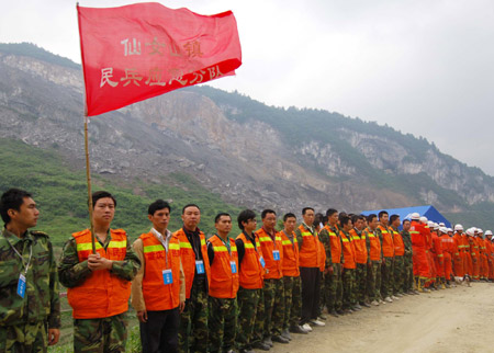 Local militia and firemen stand on the alert prior to the second blasting in Wulong County of southwest China's Chongqing, on June 7, 2009. The second blasting was carried out at around 1:00 PM on Sunday to enable the drilling of a hole 40 meters deep to send food and air to 27 trapped miners who could still be alive after Friday's massive landslide.