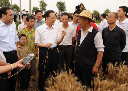 Chinese Premier Wen Jiabao (Central Left, front), who is also a member of the Standing Committee of the Political Bureau of the Communist Party of China (CPC) Central Committee, talks with farmers in Fengdian Village, Doumen Town of Xi'an, capital of northwest China's Shaanxi Province, on June 6, 2009. Wen paid a visit to Xi'an from June 5 to 7.