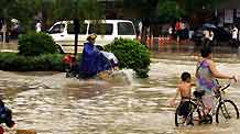 Pedestrians and vehicles wade through a flooded street in the downtown of Zhanjiang, south China's Guangdong Province, on June 7, 2009. The city of Zhanjiang has been heavily inundated after being hit by a heavy rainstorm, leaving the traffic in difficulty.