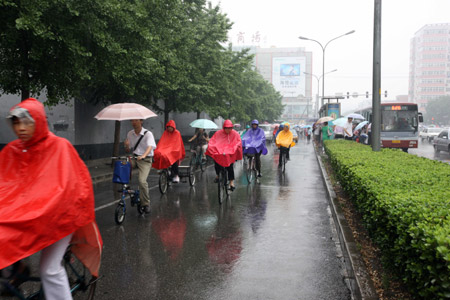 People ride bicycles in rain in Beijing, on June 8, 2009. It rains in Beijing on Monday.