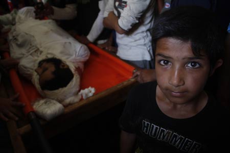 A Palestinian boy sits next to the body of Palestinian militant Taher Easa during his funeral in Rafah in the southern Gaza Strip, on June 8, 2009.At least four Palestinians were killed Monday morning in clashes with Israeli army in the eastern Gaza city.