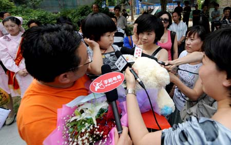 The first confirmed A/H1N1 flu patient in Henan Province (L2, front) is interviewed by the journalists as she leaves the hospital in Zhengzhou, capital of central China's Henan Province, on June 9, 2009. The 3-year-old girl was discharged from hospital on Tuesday. She arrived in Zhengzhou on May 29 from the United States and was confirmed as the first A/H1N1 case in Henan on June 1. 