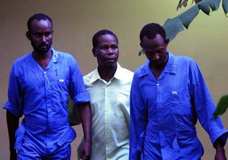 Two suspected Somali pirates are guarded by a Kenyan policeman (C) in the port city of Mombasa, east Kenya, on June 8, 2009. The Swedish Navy on Monday handed over to Kenya seven suspected pirates who were arrested on May 26 as they attacked a merchant vessel in the Gulf of Aden. 