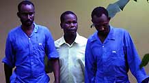 Two suspected Somali pirates are guarded by a Kenyan policeman (C) in the port city of Mombasa, east Kenya, on June 8, 2009. The Swedish Navy on Monday handed over to Kenya seven suspected pirates who were arrested on May 26 as they attacked a merchant vessel in the Gulf of Aden.