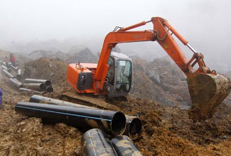A digger excavates the path to lay water pipes to release a barrier lake caused by a massive landslide at Jiwei Mountain, in Wulong County of southwest China's Chongqing Municipality, on June 9, 2009. The local government has relocated villagers threatened by the lake which increased to more than 10,000 steres due to continuous rainfall. 