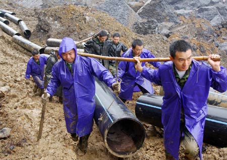 Rescue workers lay water pipes to release a barrier lake caused by a massive landslide at Jiwei Mountain, in Wulong County of southwest China's Chongqing Municipality, on June 9, 2009. The local government has relocated villagers threatened by the lake which increased to more than 10,000 steres due to continuous rainfall.