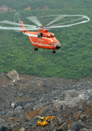 A MI-26 helicopter carries an excavator to the landslide site of Jiwei Mountain, in Wulong County, southwest China's Chongqing Municipality, on June 11, 2009. The MI-26 heavy-lifting helicopter has begun carrying heavy machineries needed in the search for 63 people missing in a massive landslide on Friday. The heavy machineries will be used to remove giant rocks that buried two entrances to an iron ore mine, where 27 miners are believed to be trapped.