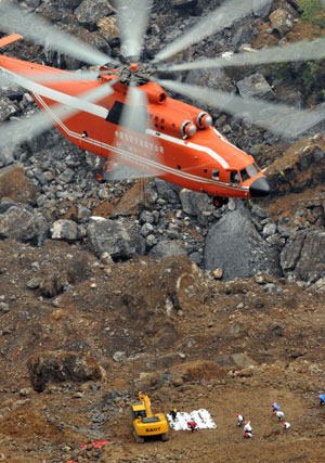 A MI-26 helicopter hovers to unload an excavator at the landslide site of Jiwei Mountain, in Wulong County, southwest China's Chongqing Municipality, on June 11, 2009. The MI-26 heavy-lifting helicopter has begun carrying heavy machineries needed in the search for 63 people missing in a massive landslide on Friday. The heavy machineries will be used to remove giant rocks that buried two entrances to an iron ore mine, where 27 miners are believed to be trapped.