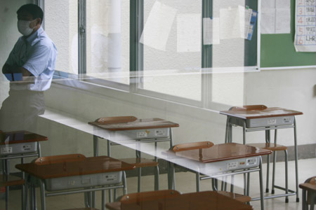 A teacher rests outside an empty classroom in the private Seisoku High School in Tokyo, capital of Japan, on June 12, 2009. The first A/H1N1 flu group infections in Tokyo were confirmed on Thursday, with nine students and three teachers of the high school in Minato Ward contracting the disease. The high school will be closed for one week from Thursday due to the outbreak. 