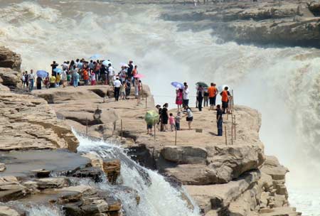 Sightseers view the spectacular torrential Hukou (Kettle Mouth) Waterfall on the Yellow River in Yichuan, northwest China's Shaanxi Province, on June 14, 2009. 