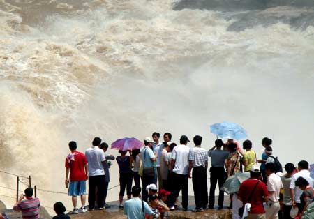 Sightseers view the spectacular torrential Hukou (Kettle Mouth) Waterfall on the Yellow River in Yichuan, northwest China's Shaanxi Province, on June 14, 2009.