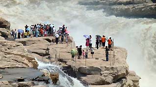 Sightseers view the spectacular torrential Hukou (Kettle Mouth) Waterfall on the Yellow River in Yichuan, northwest China's Shaanxi Province, on June 14, 2009.